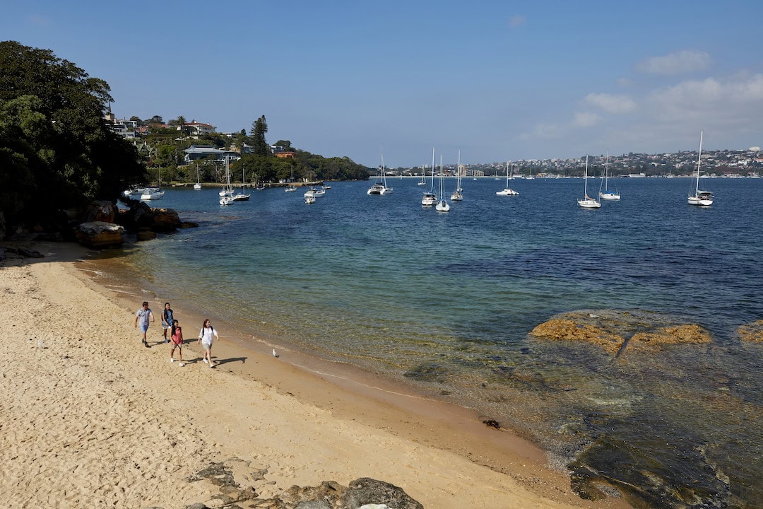 Friends talking a stroll at Milk Beach, one of the top Sydney Harbour beaches. Photo: Destination NSW.