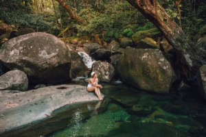 Lady sits on a rock in the Daintree Rainforest.