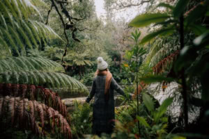 Woman pushes through the plants and foliage of Styx Valley to see the view.